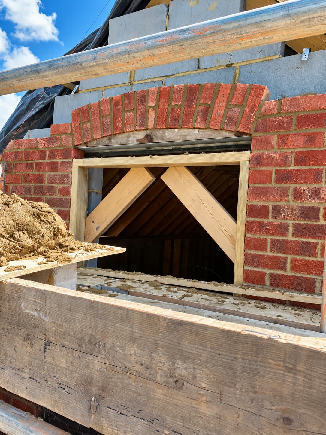 Segmental red brick arch turned over timber centring above a gable window, London