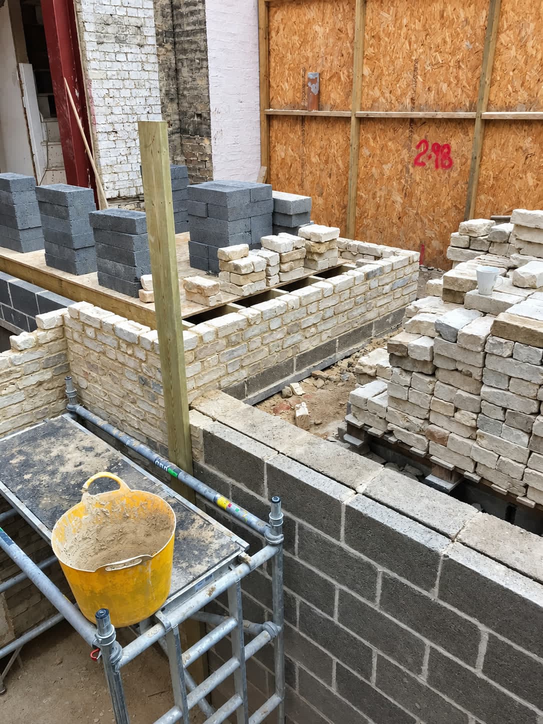 Blockwork inner leaf with stock brick outer leaf and bricks stacked ready, London