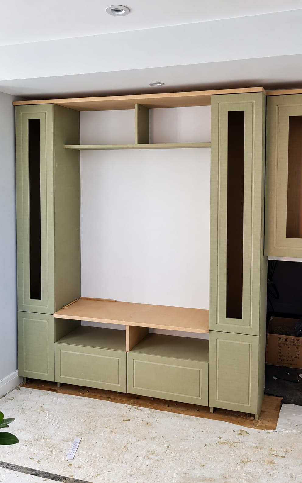 Built-in media wall carcass with shelving and cupboards, London