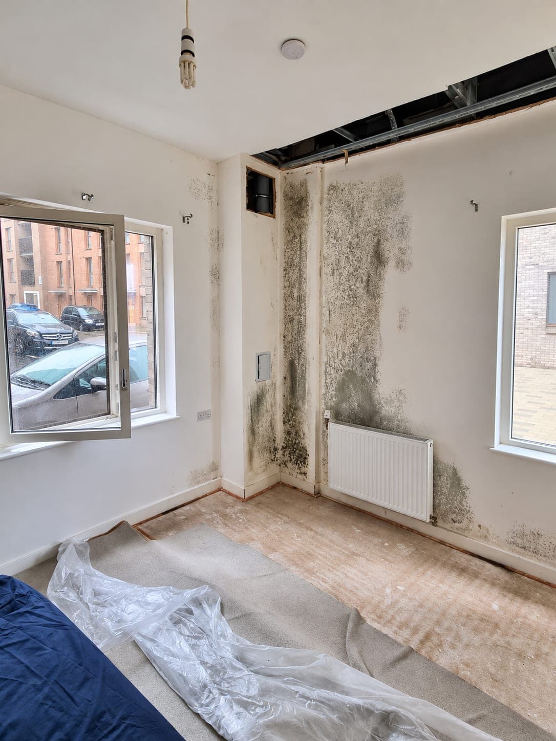 Damp and mould around a window reveal before treatment, London