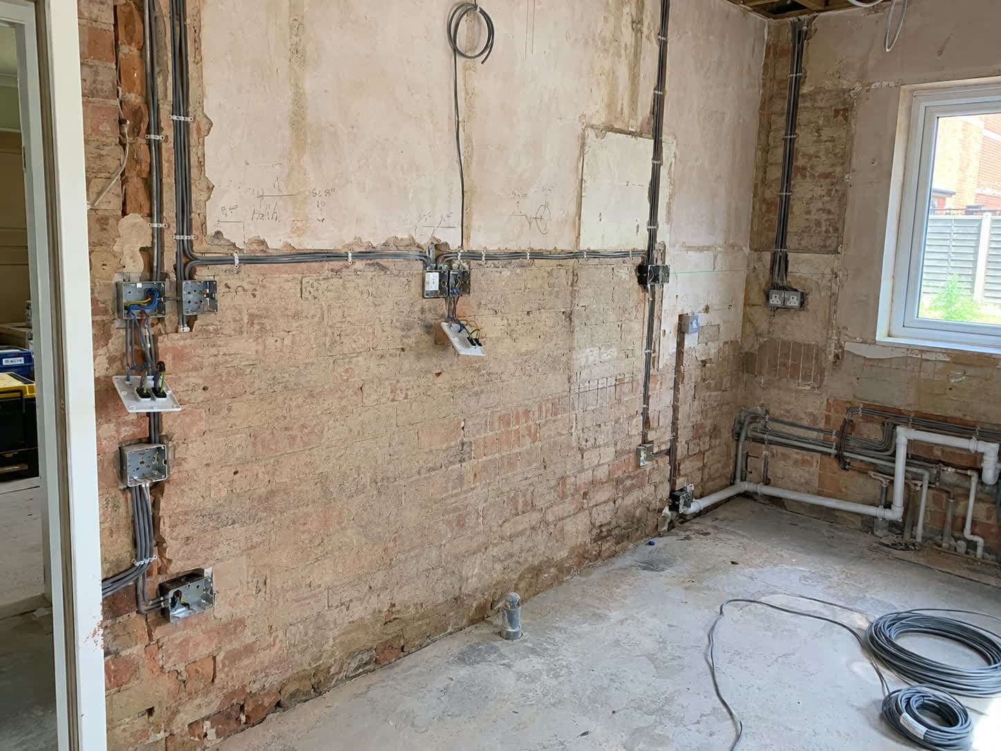 Socket boxes and cable runs chased into a brick wall during a rewire, London