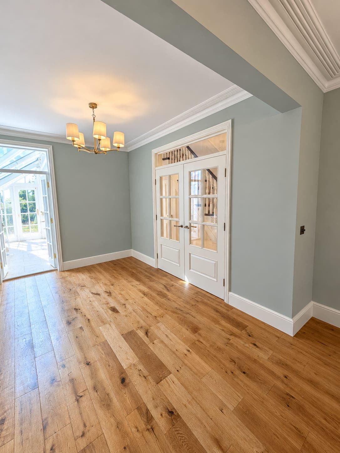 Engineered oak flooring in a room with sage walls and glazed garden doors, London