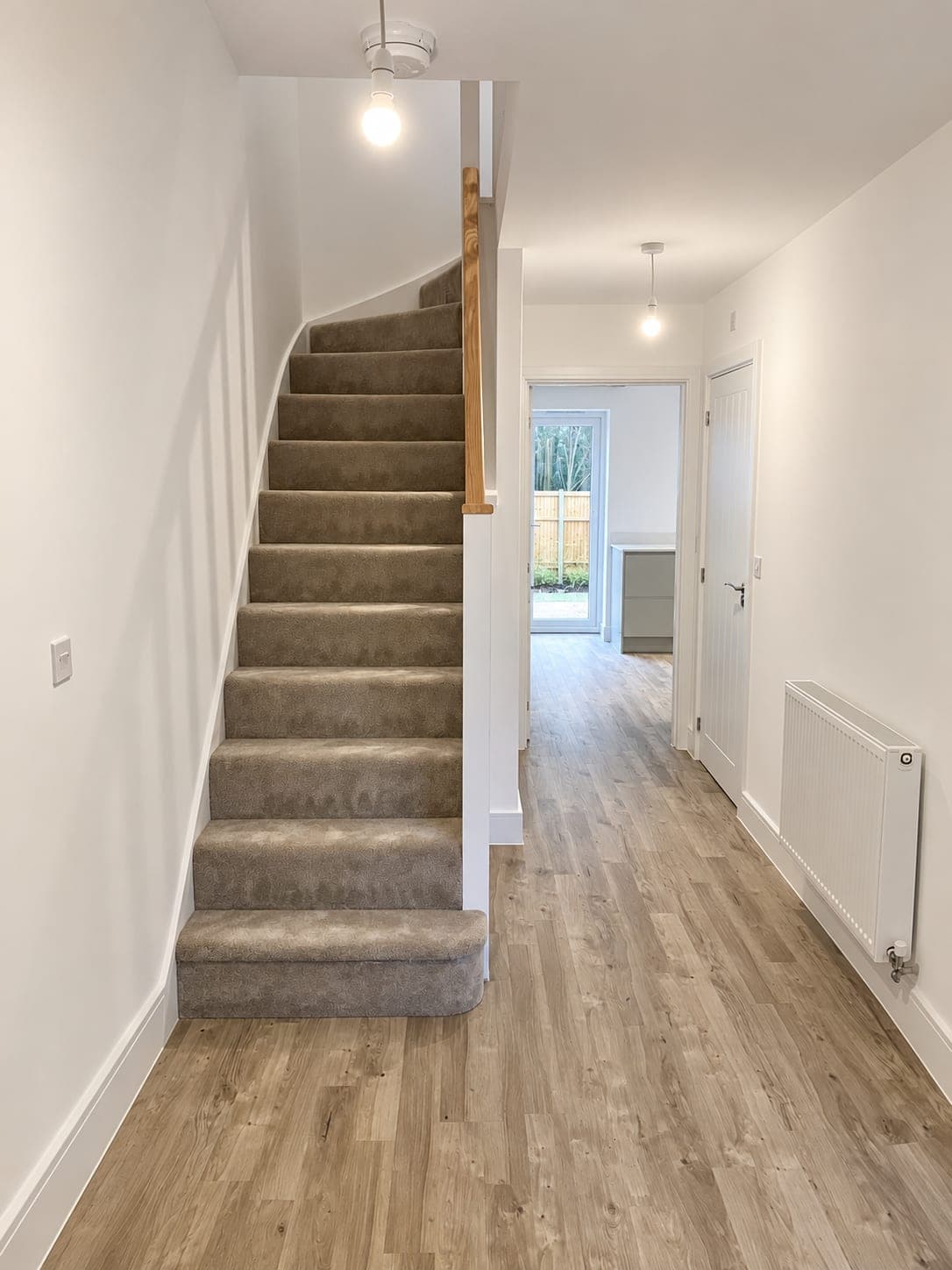 Plank flooring running through a hallway past a carpeted staircase, London