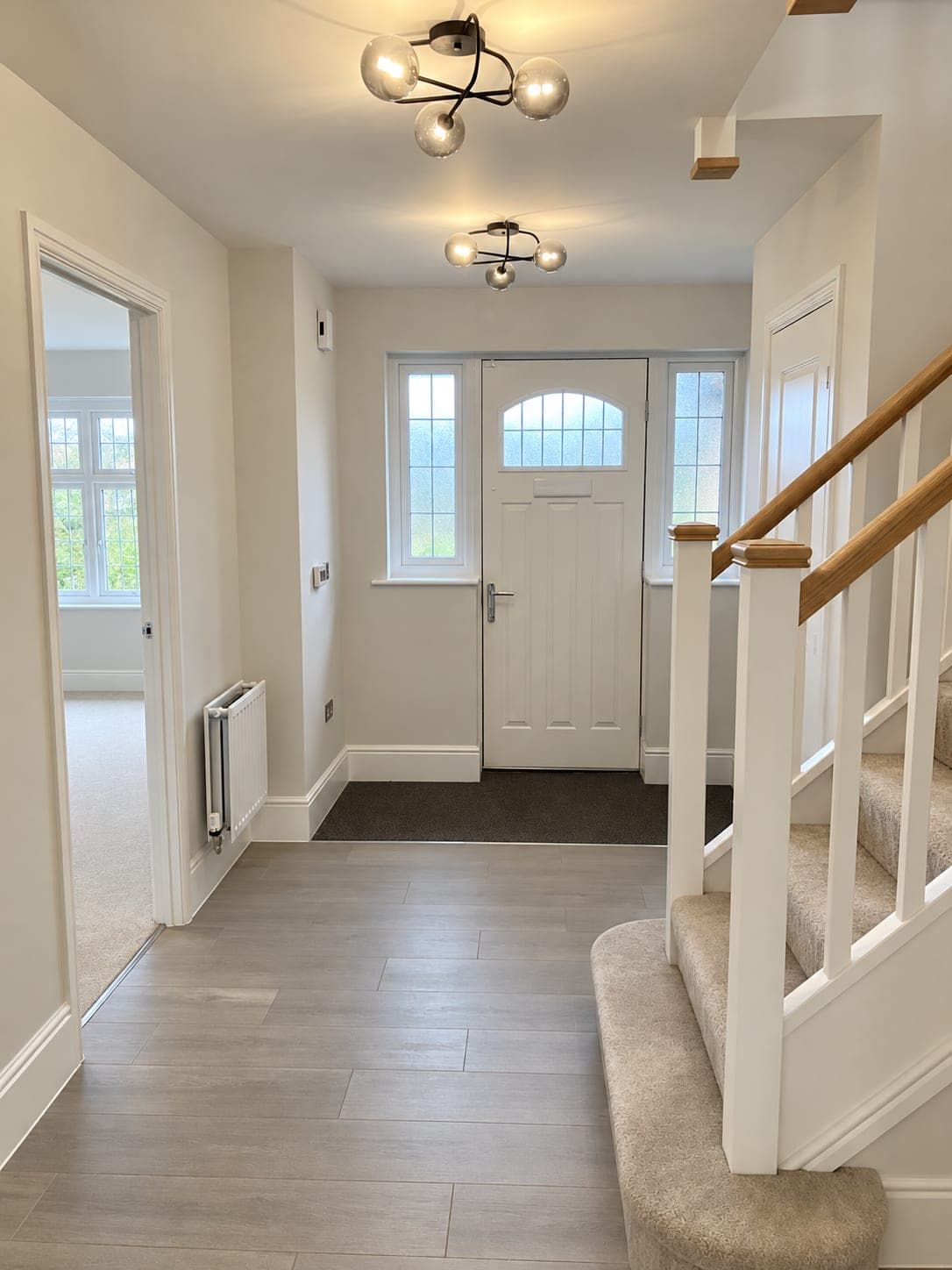 Herringbone flooring in an entrance hall with a panelled front door, London