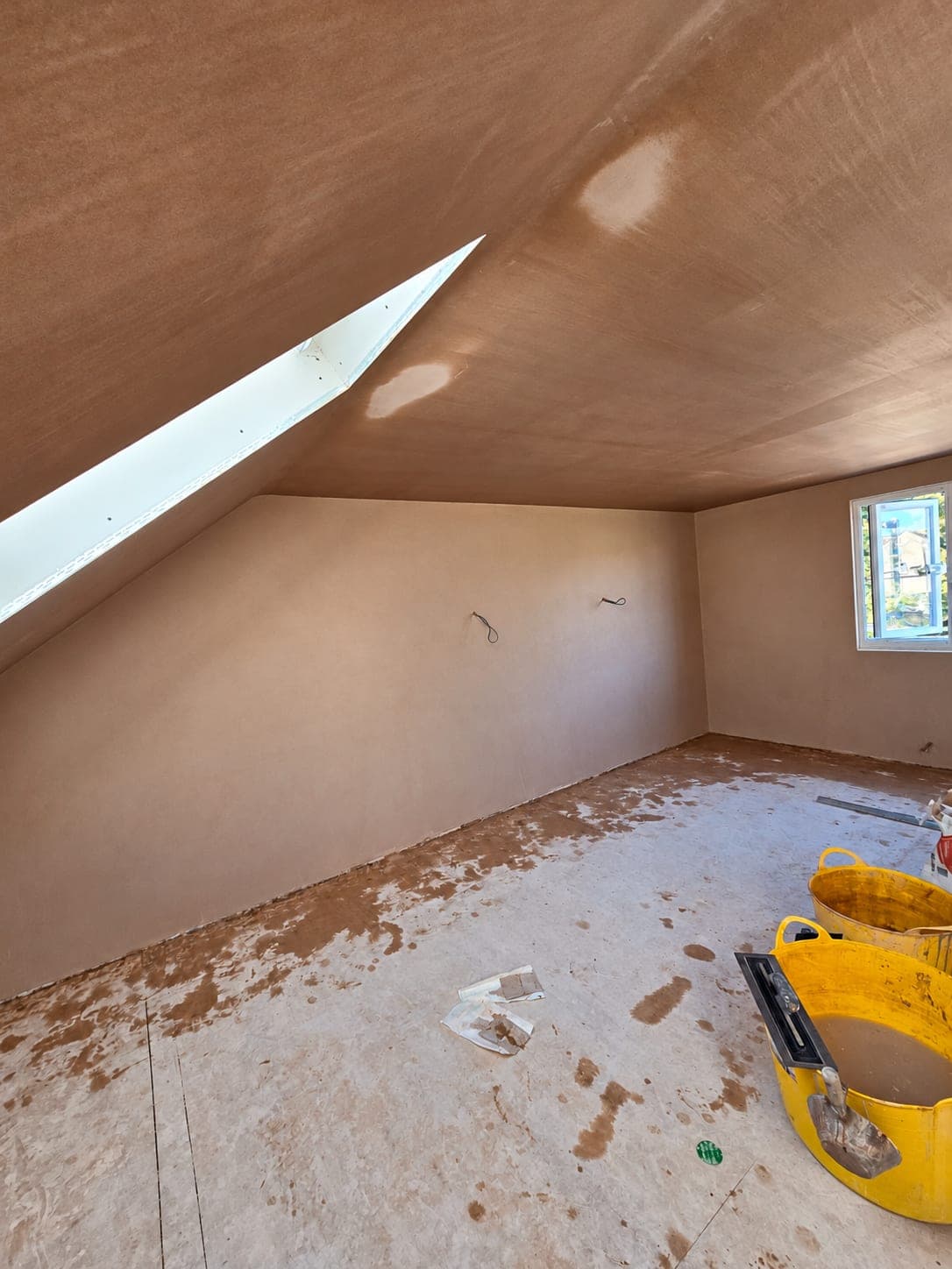 Loft room walls and sloped ceiling skimmed out under a rooflight, London