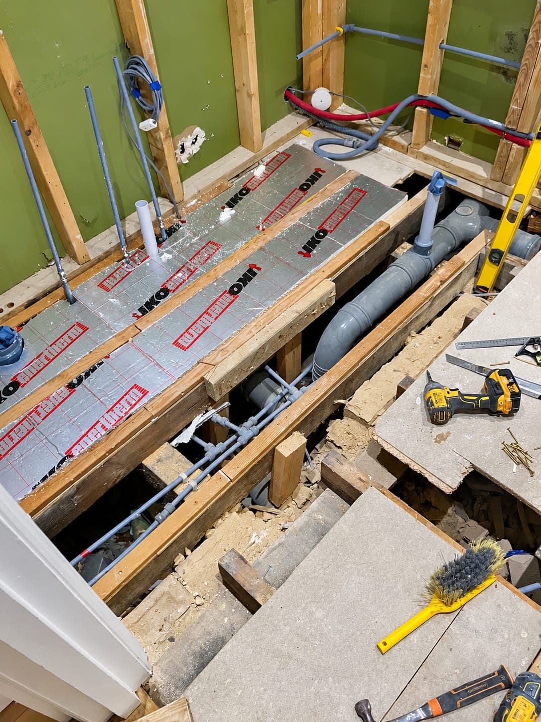 Long pipe run laid under a lifted floor before boarding over, London