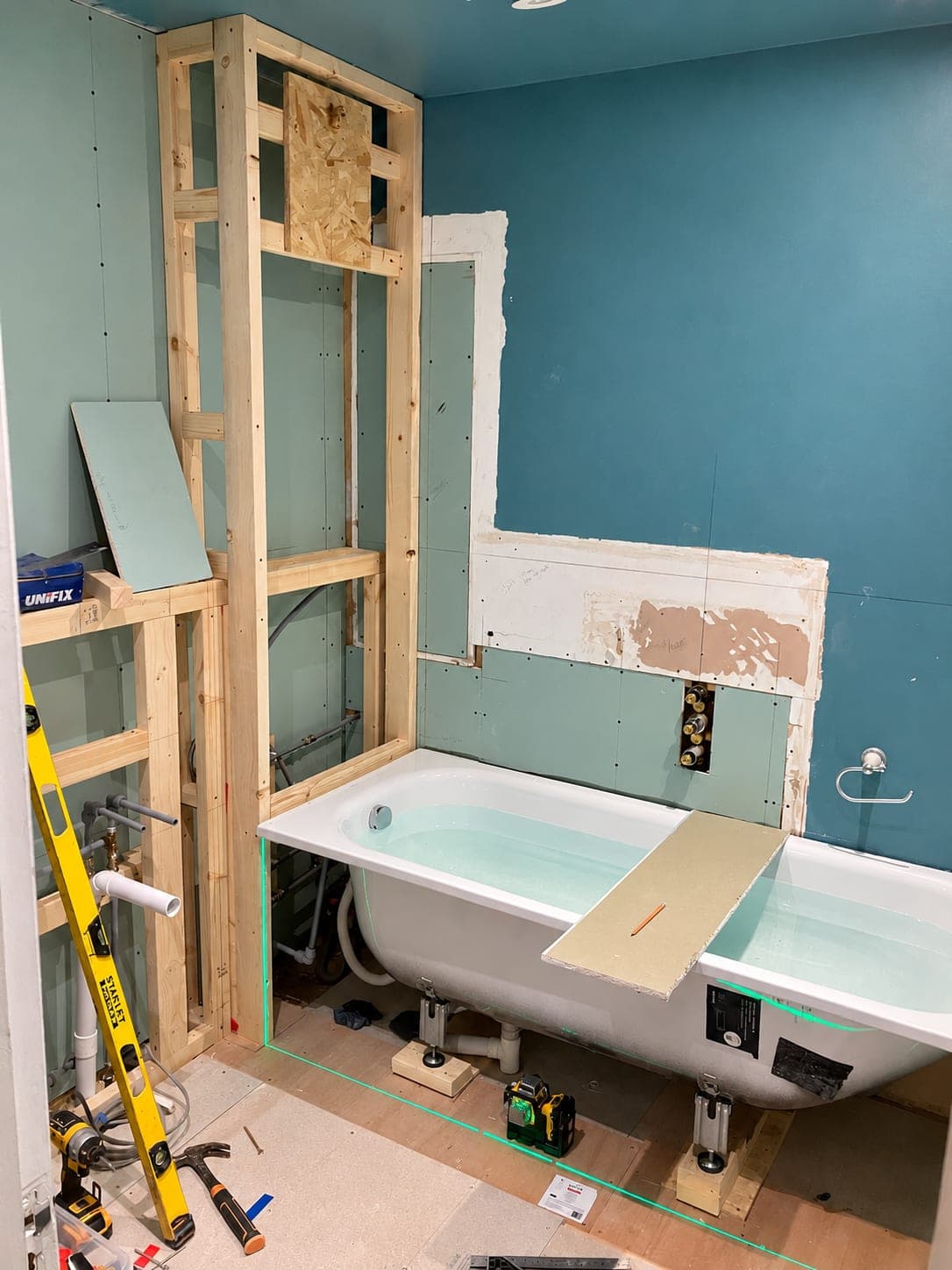 Bath set into a framed recess with pipework below, London