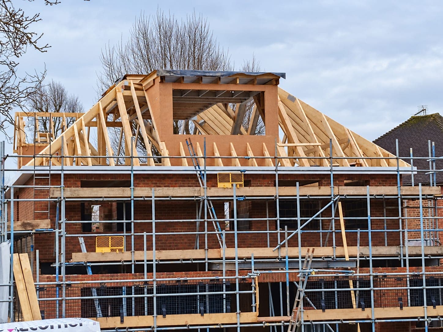 New timber roof structure framed up behind scaffold, London