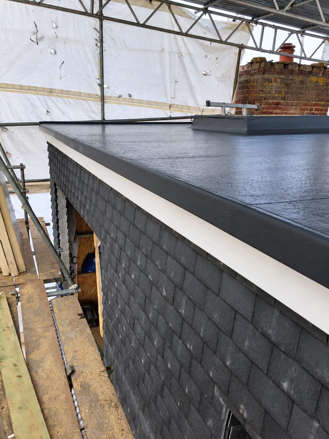 Flat roof covered in dark membrane with trim and fascia fitted, London