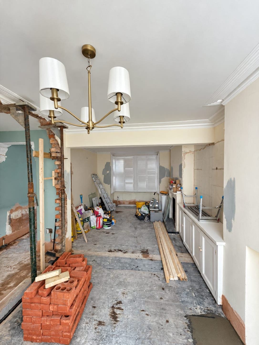 Wall opened up in a finished room with brickwork exposed and bricks stacked ready, London