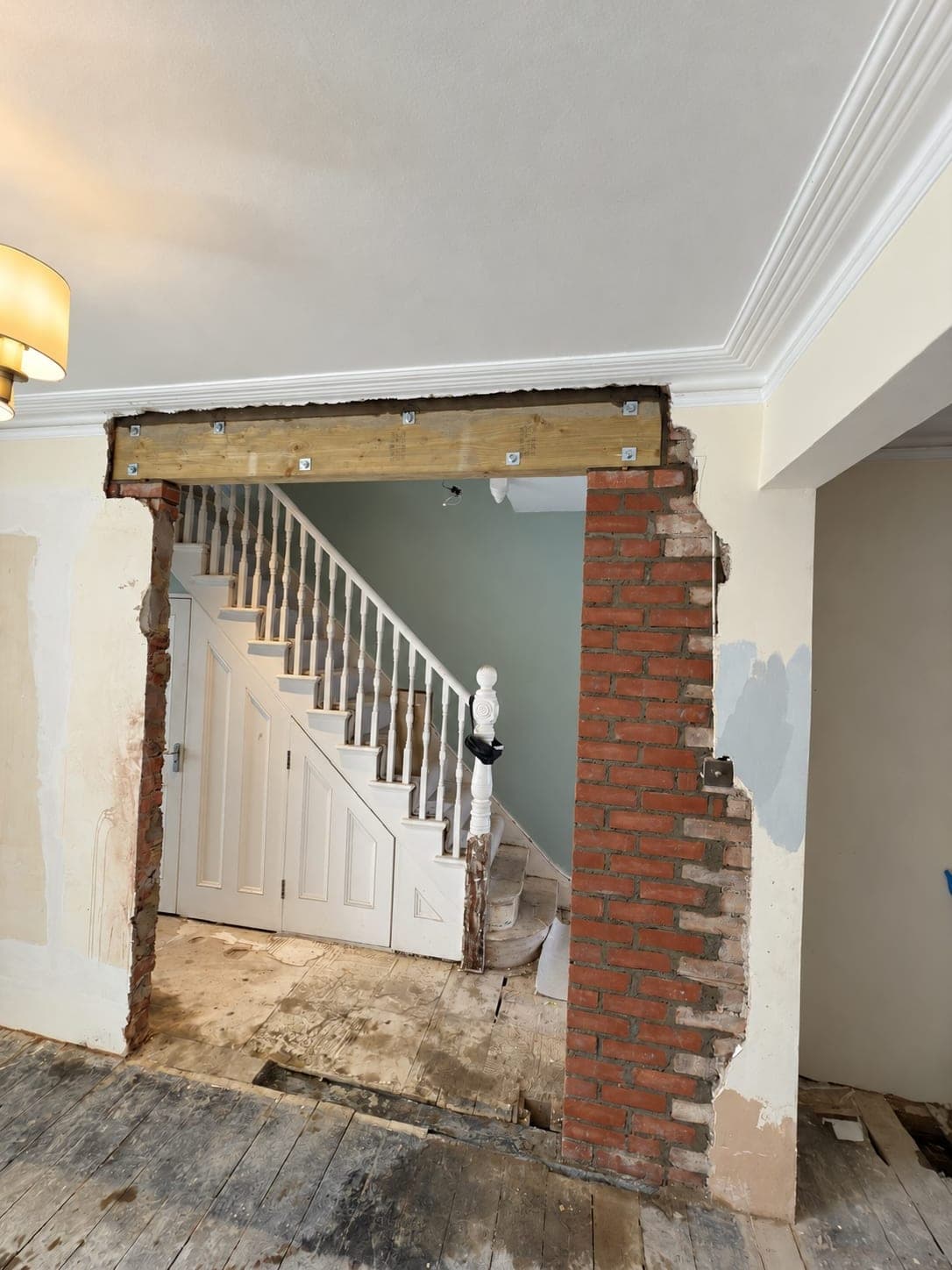Opening cut through a wall beside a staircase with brickwork exposed, London