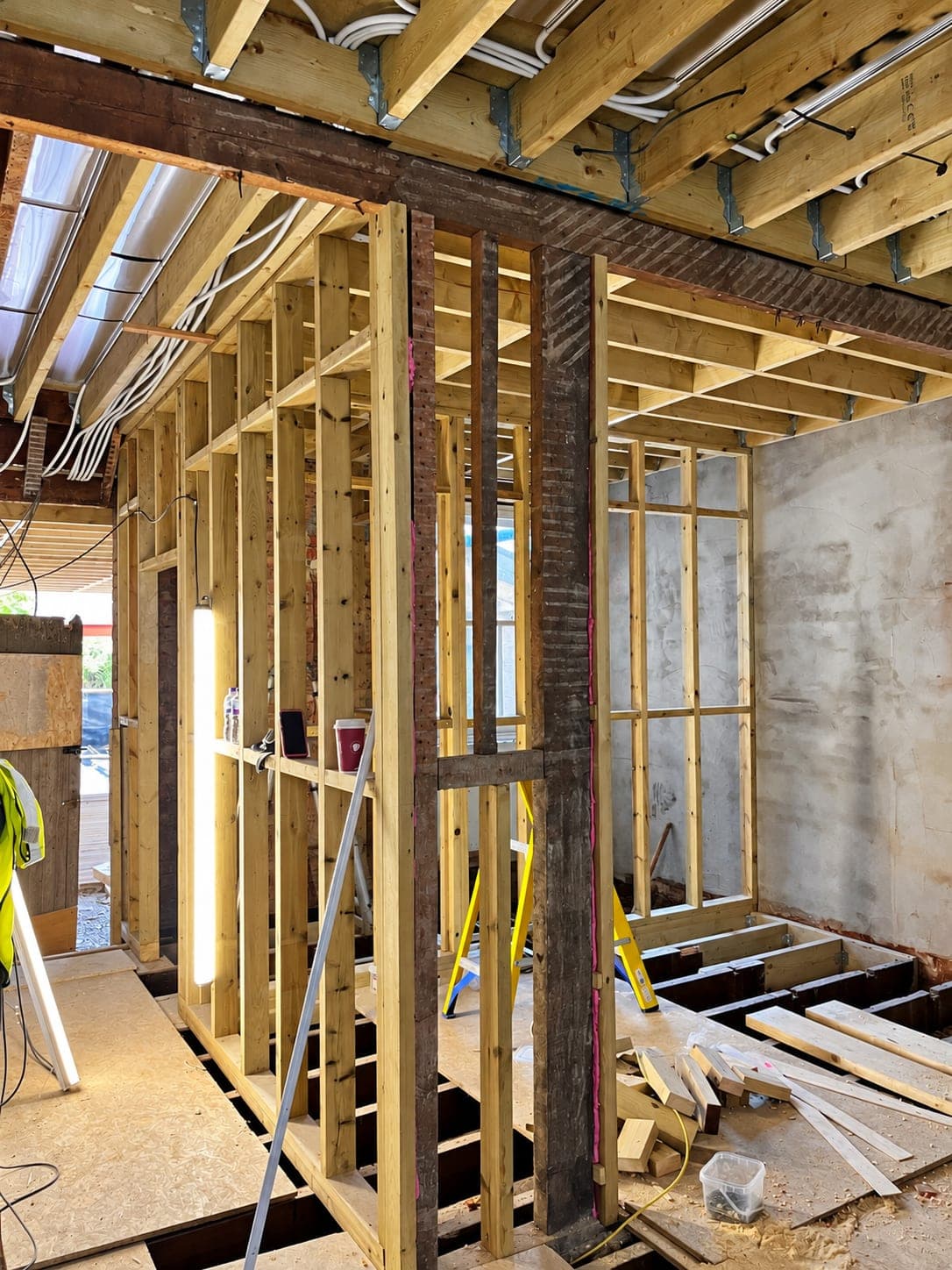 Steel column built into a new stud wall with joists exposed above, London