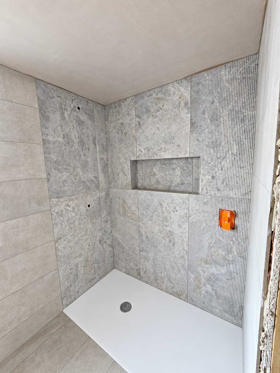 Stone-effect tiled shower enclosure with a recessed niche and low-profile tray, London