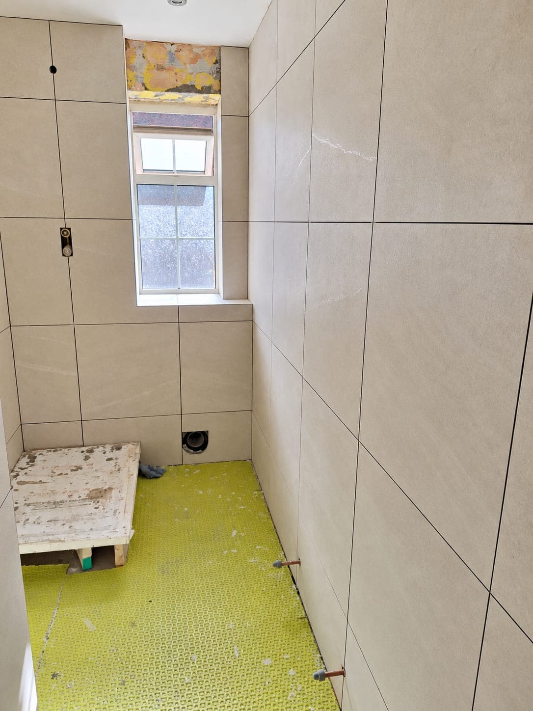 Large-format tiling worked around a bathroom window reveal, London