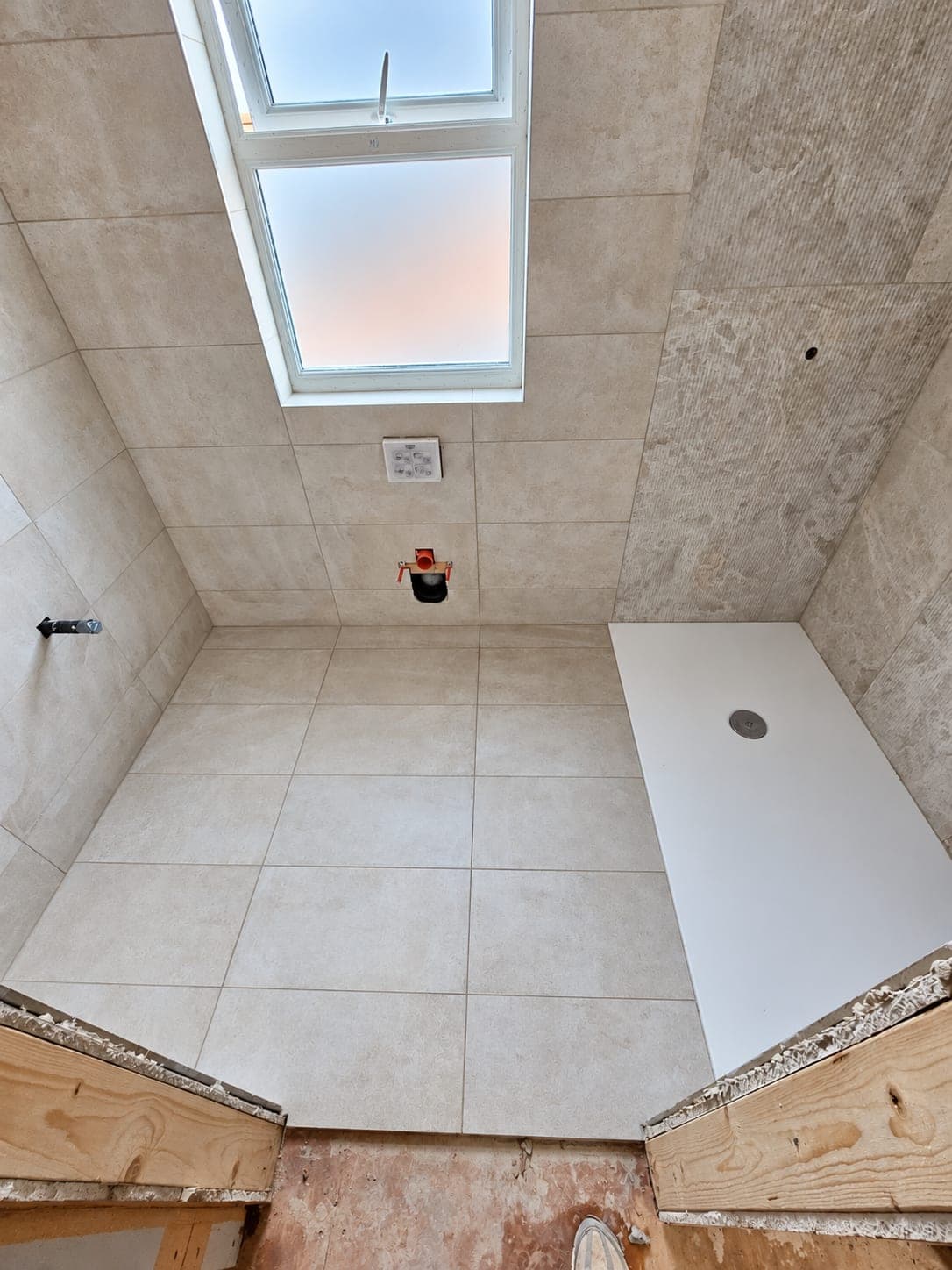Loft bathroom tiled out under a rooflight with a shower tray in place, London