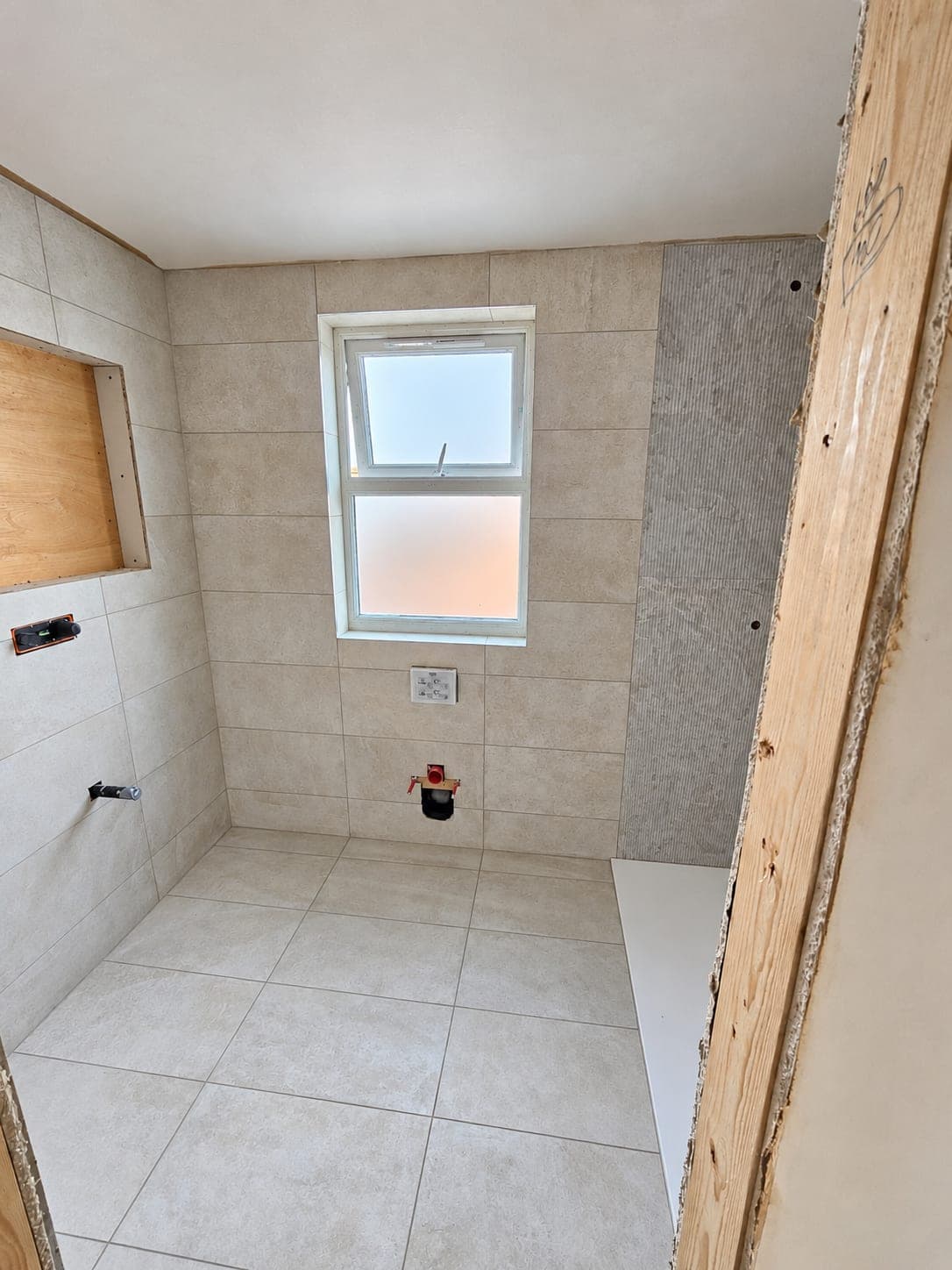 Tiled bathroom walls with a shower tray set into the floor, London