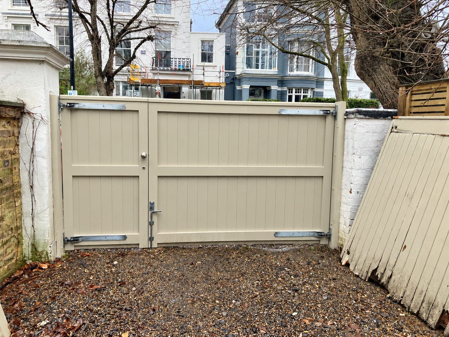 Pair of tall painted timber gates hung between rendered piers, London
